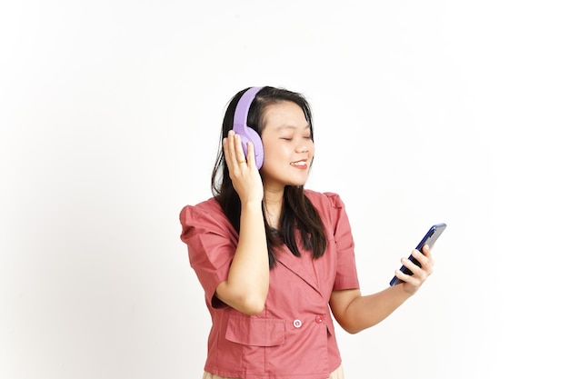 Escuchar música desde el teléfono inteligente con el uso de auriculares de hermosa mujer asiática aislada en blanco