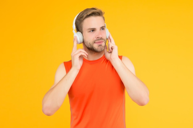 Escuche con interés el entrenamiento en línea con el entrenador, relájese después del entrenamiento, un joven guapo con auriculares, deporte moderno y fitness, escuche música, un chico atlético con ropa deportiva, nueva tecnología digital.