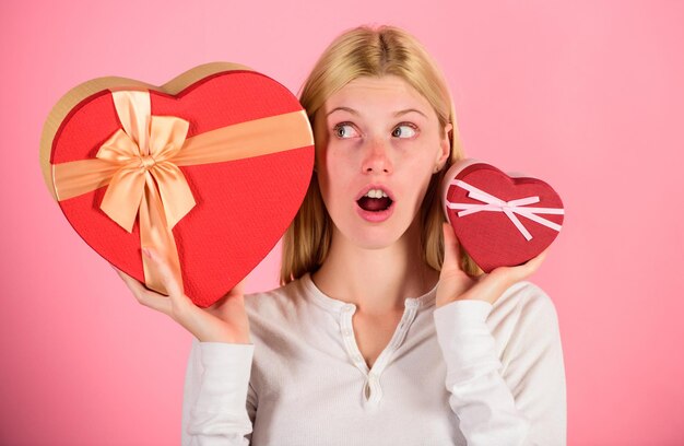 Escuche a su corazón La niña decide qué regalo le gusta más Gran sorpresa y regalo pequeño Elija un regalo romántico para ella La mujer sostiene cajas de regalo grandes y pequeñas en forma de corazón Cuál prefiere