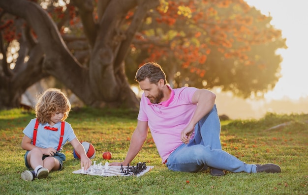 Escuela de ajedrez para niños familia feliz al aire libre padre e hijo jugando al ajedrez en el jardín de primavera
