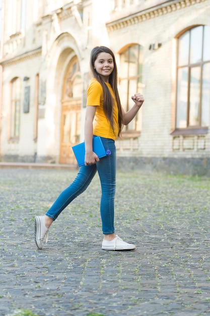 Escuela para el aprendizaje creativo Niño feliz de regreso a la escuela Niña sostiene un libro al aire libre Tiempo escolar Escuela y educación Día del conocimiento 1 de septiembre Inicio Aprendizaje alegre