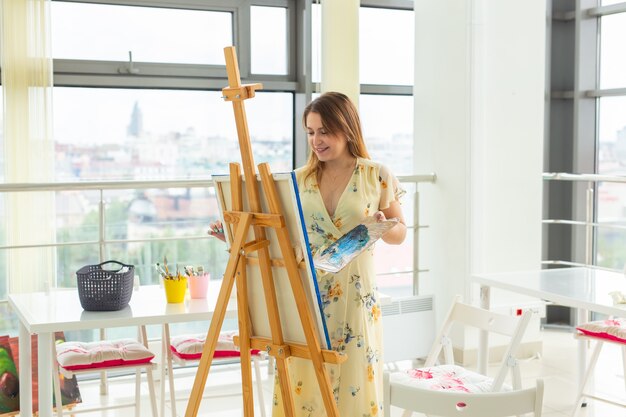 Escuela de arte, facultad de artes, educación para grupo de jóvenes estudiantes. Feliz joven sonriente, niña aprendiendo a pintar.