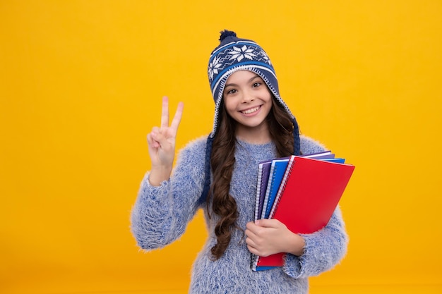 Escuela de invierno Colegiala adolescente con libros en ropa de otoño sobre fondo de estudio aislado amarillo Cara feliz emociones positivas y sonrientes de chica adolescente