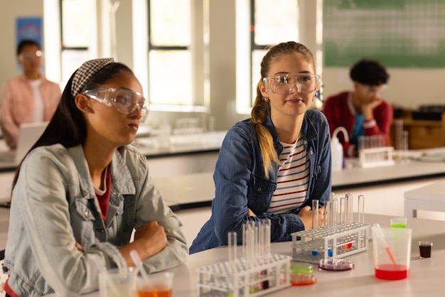 En la escuela secundaria, adolescentes con gafas de seguridad asistiendo a la clase de química.