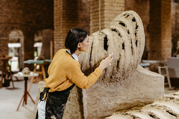 Escultor profesional de mujer de mediana edad hermosa trabajando en una hermosa escultura.