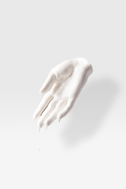 Escultura abstracta en forma de brazo humano en líquido blanco sobre blanco