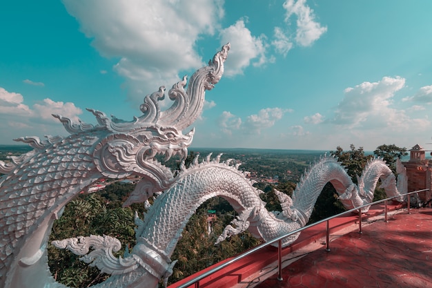 Foto la escultura de blanco naga prayanak con fondo de cielo azul y nubes.