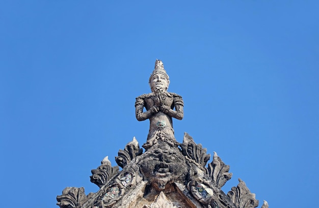 Escultura de la deidad en la parte superior del frontón de la antigua sala de ordenación del templo budista Wat Chomphuwek Tailandia