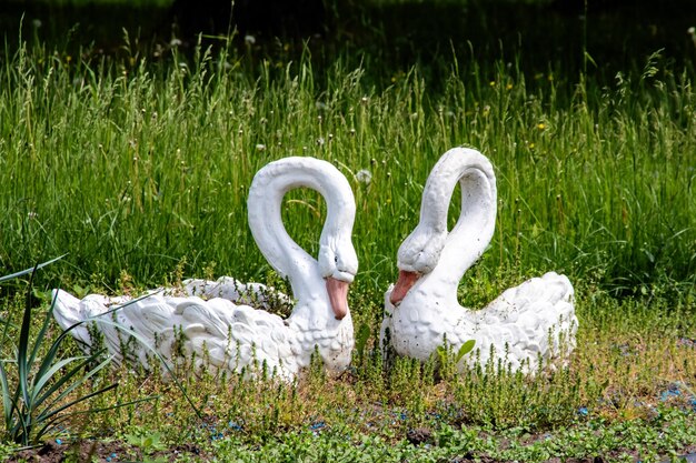 Escultura de dos cisnes en un macizo de flores