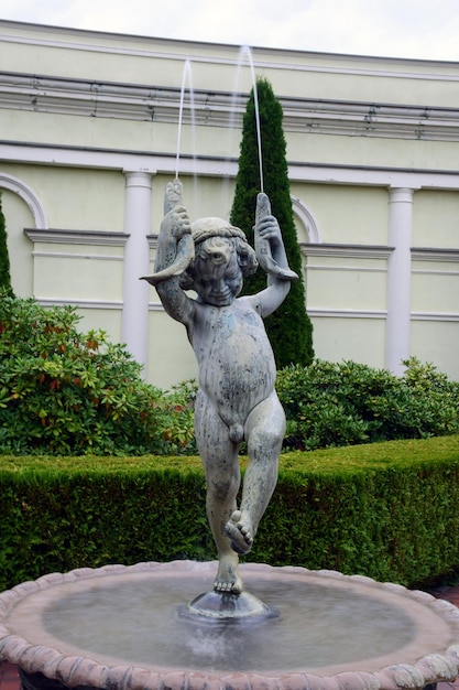 Escultura de una fuente en forma de niño con cuernos de los que brota agua