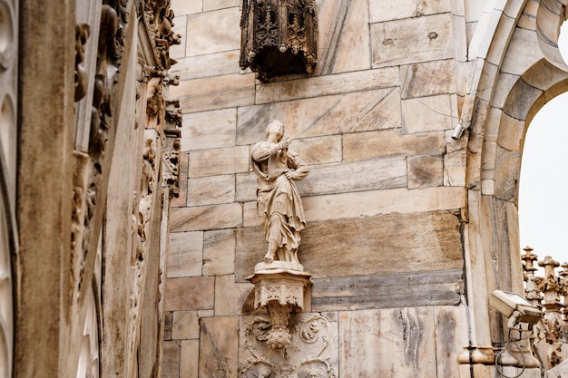 Escultura de una mujer en el pedestal de la fachada de la catedral de milán italia