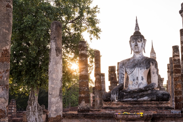 Escultura que está a imagem de buddha de Wat Mahathat no parque nacional de Sukhothai em Tailândia no por do sol.