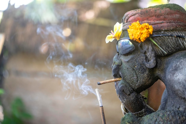 Foto escultura tradicional balinesa con gafas de sol y un cigarrillo en la calle isla bali indonesia cerrar