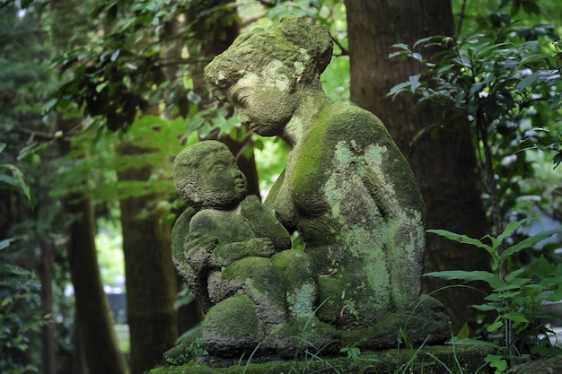 Esculturas de pedra de mãe e filho dentro da escura floresta japonesa