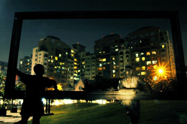 Esculturas en el parque contra los edificios por la noche