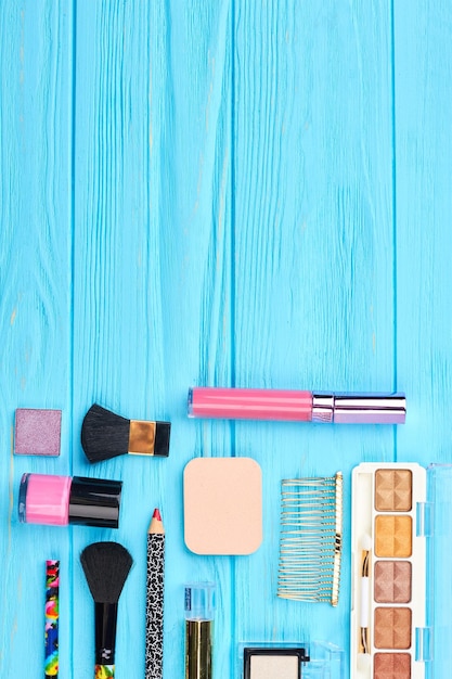 Esenciales cosméticos sobre fondo de madera. Cosméticos y accesorios de belleza en mesa de madera azul, espacio de copia.