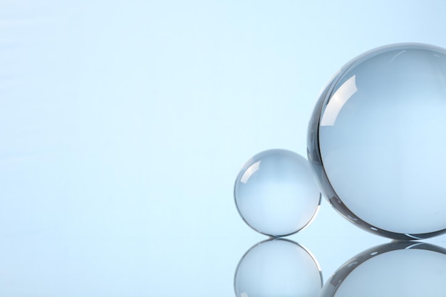 Esferas de vidrio transparentes en la superficie del espejo contra un fondo claro Espacio para el texto