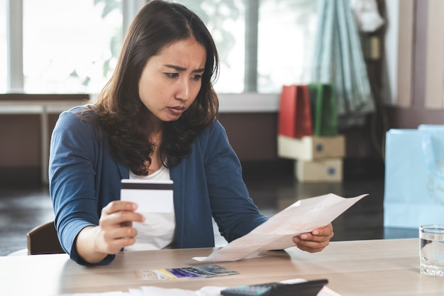 Esforço asiático da mulher com débito do cartão de crédito.