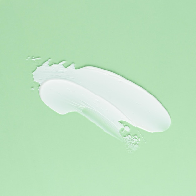 Foto esfregaço de creme branco para rosto e corpo em um fundo verde