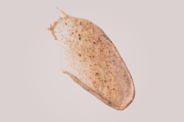 Foto esfregue a amostra de esfregaço isolada em fundo bege descascando a mancha de creme com partículas esfoliantes produto cosmético para a pele com amostra de partículas abrasivas textura de esfoliação nua suave