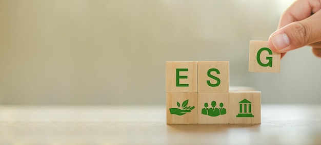 ESG-Konzepte zu Umwelt, Gesellschaft und Governance Organisation für nachhaltige Entwicklung Hand, die einen ESG-Holzblock mit einem ESG-Symbolpiktogramm auf dem Hintergrund des Kopierraums hält