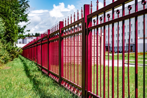 Esgrima forjada de metal fundido decorativo rojo cerca de un edificio público.