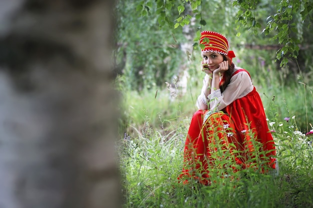 Eslavo em trajes tradicionais está sentado na natureza