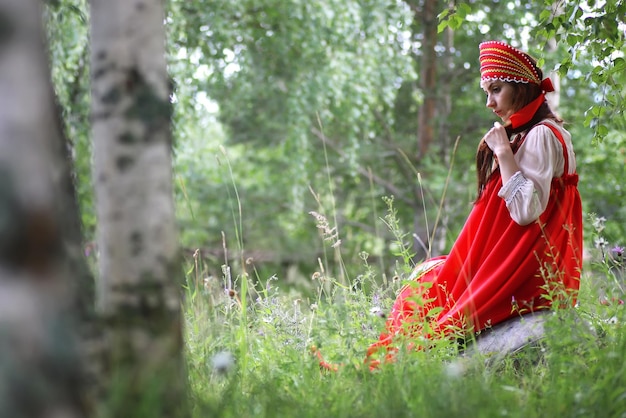 Eslavo em trajes tradicionais está sentado na natureza