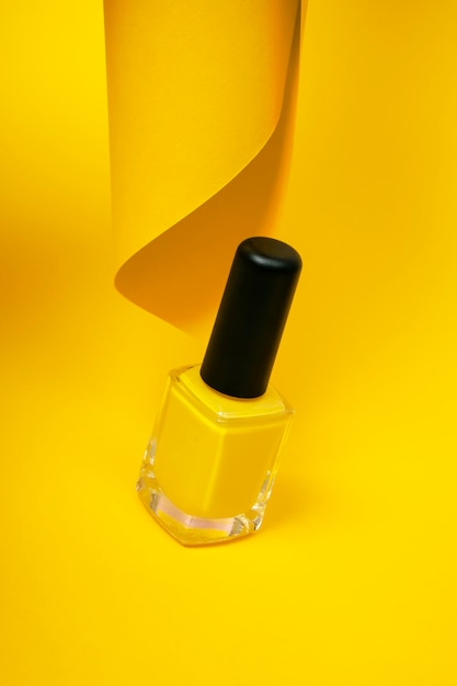 Esmalte de uñas amarillo aislado sobre fondo amarillo Concepto estético