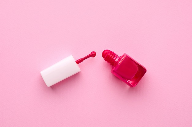 Esmalte de uñas cosmético de color rosa con pincel sobre rosa