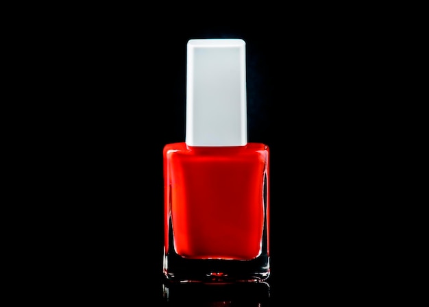 Esmalte de uñas rojo en botella en el espacio de fondo negro brillante para el enfoque selectivo de texto