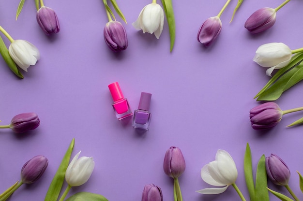 Esmalte de uñas de tulipanes frescos de primavera sobre fondo violeta