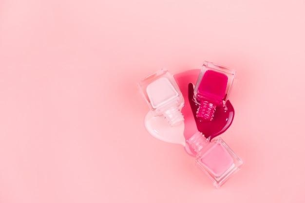 Foto los esmaltes de uñas gotean sobre una superficie rosa