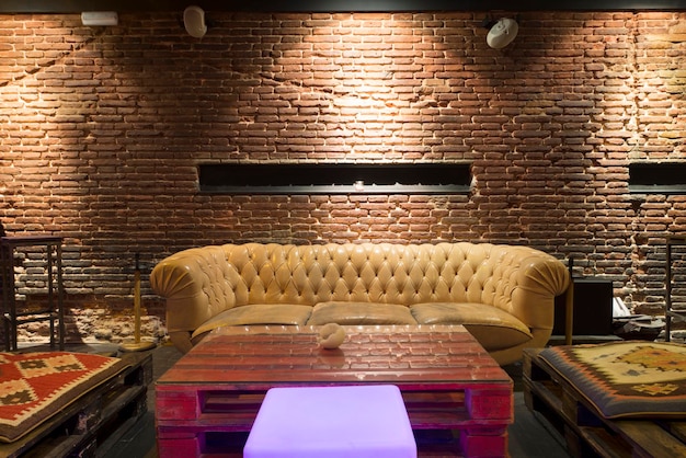 Foto un espacio de bar relajante con sillones tapizados en cuero color crema brillante estilo chester y una mesa de centro hecha con tarimas de madera