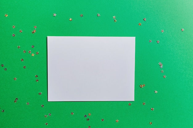 Espacio en blanco de papel sobre fondo verde con confeti