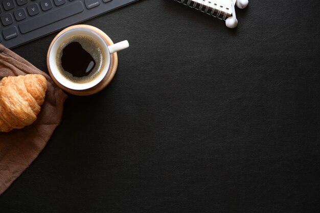 Espacio de escritorio de la oficina en casa con café, croissant y espacio de copia