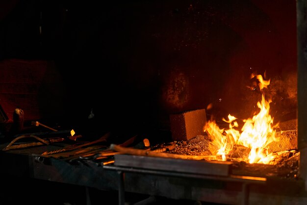 Espacio interior del horno de herrero con fuego ardiente y herramientas de forja que se encuentran cerca