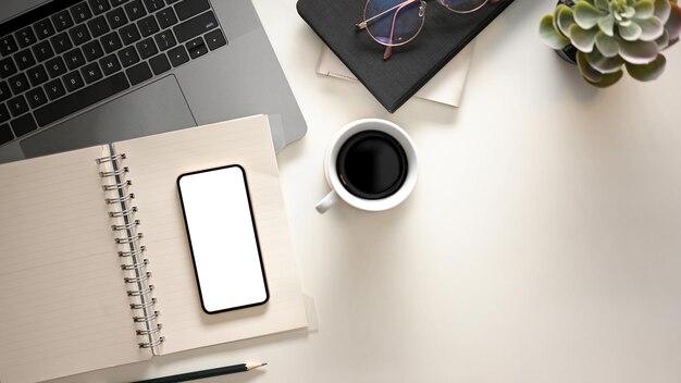 Un espacio de trabajo con accesorios, pantalla en blanco del teléfono inteligente portátil y espacio de copia sobre fondo blanco