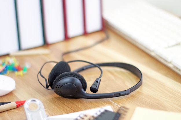 Espacio de trabajo con auriculares y equipos de oficina sobre fondo de trabajo de escritorio de madera