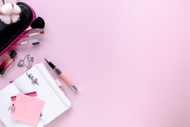 Foto espacio de trabajo de blogger de moda con laptop y accesorios femeninos, productos cosméticos en mesa de color rosa pálido.
