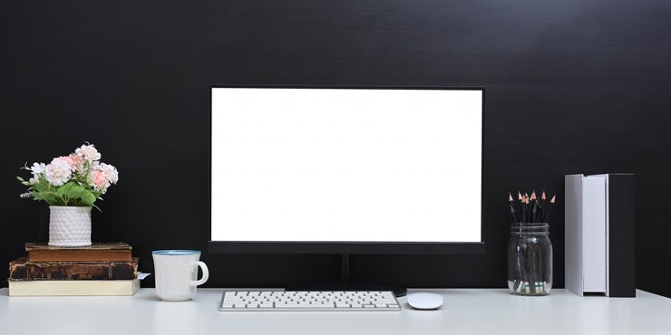 Foto un espacio de trabajo cómodo está rodeado por un monitor de computadora de pantalla blanca en blanco y varios equipos