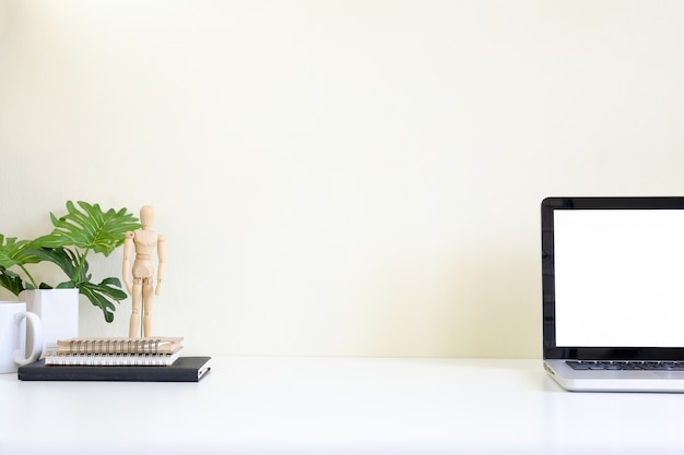 Foto espacio de trabajo con la computadora portátil en la mesa blanca y el espacio de maqueta de fondo amarillo.