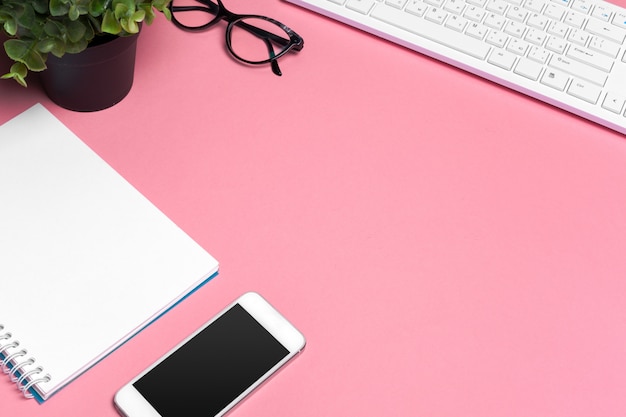 Espacio de trabajo creativo rosa para mujer con teclado de computadora y suministros, vista superior