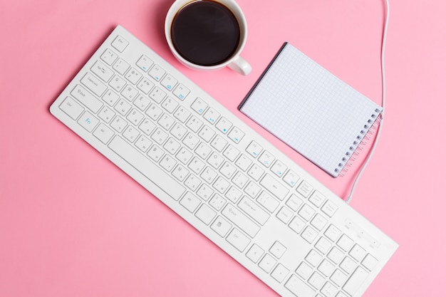 Espacio de trabajo creativo rosa para mujer con teclado de computadora y suministros, vista superior