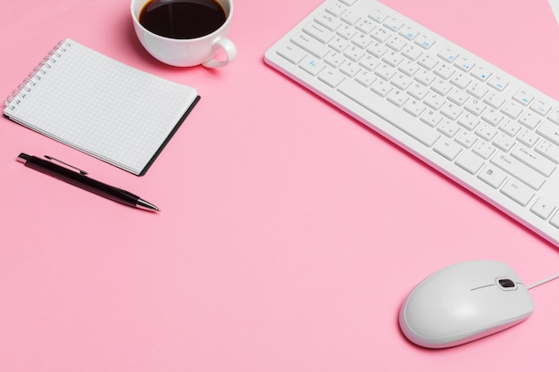 Espacio de trabajo creativo rosa para mujer con teclado de computadora y suministros