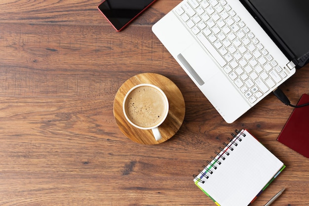 Espacio de trabajo con diario portátil y una taza de café sobre fondo de madera Lugar de trabajo de oficina elegante