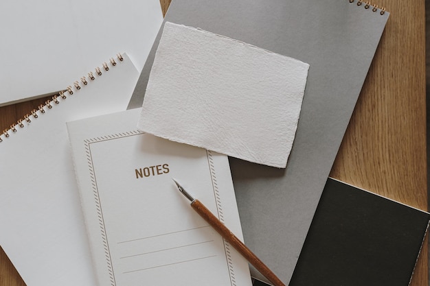 Espacio de trabajo elegante estético con tarjeta de hoja de papel en blanco de cuaderno sobre mesa de fondo de madera Concepto de arte de caligrafía Vista plana superior