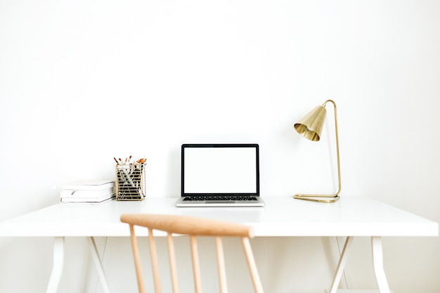 Espacio de trabajo de escritorio de oficina en casa brillante con ordenador portátil de pantalla en blanco.