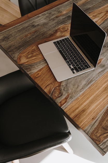 Espacio de trabajo de escritorio de oficina en casa con computadora portátil, mesa de madera maciza, silla de cuero, concepto de diseño interior moderno