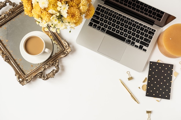 Espacio de trabajo de escritorio de oficina en casa con computadora portátil, taza de café, bandeja vintage, ramo de flores silvestres de otoño sobre fondo blanco. Endecha plana